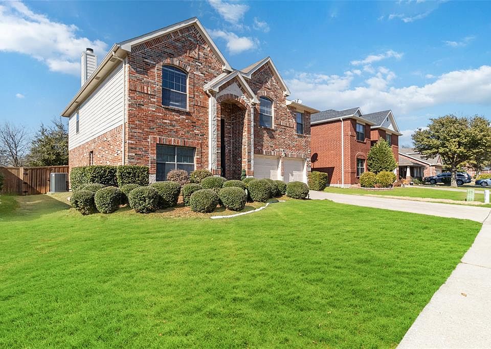 Traditional-style home with brick siding, driveway, an attached garage, a gate, and a chimney