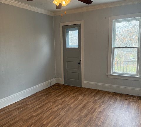 Bright living room with ceiling fan, and door to a spacious balcony