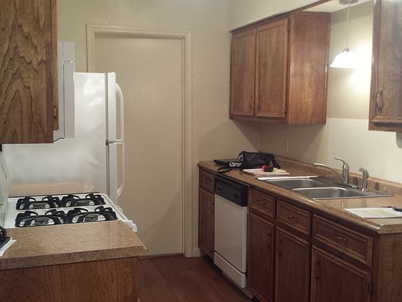 Kitchen with gas cookstove, fridge, dishwasher, microwave; door leads to laundry room.