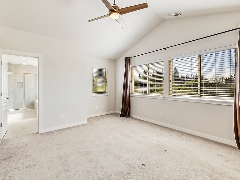Master bedroom with high vaulted ceiling and a remote controlled fan.