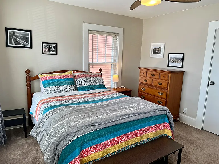 Primary bedroom, queen bed, two dressers and blackout curtains and blinds.