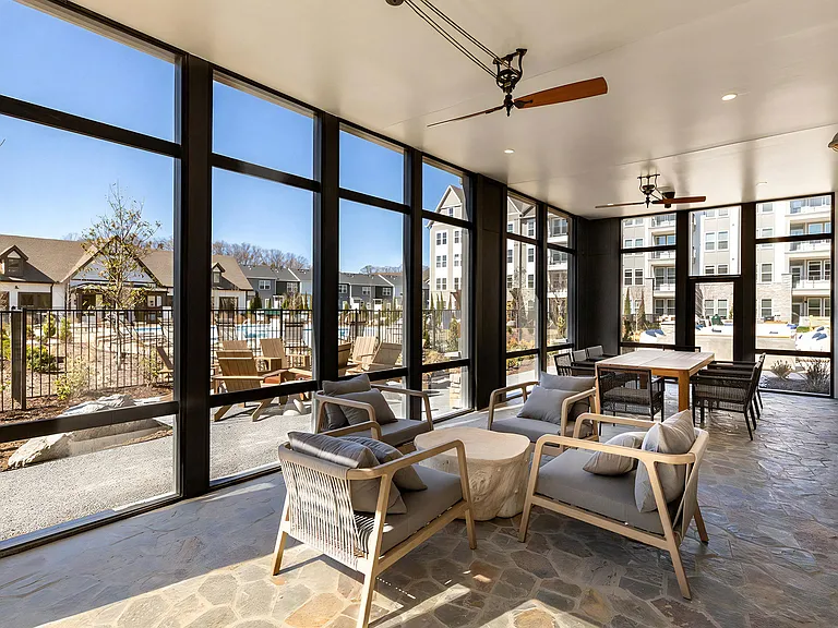 Covered Patio Lounge with Floor-to-Ceiling Windows and Cozy Seating