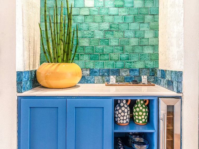 Custom wet bar with handcrafted green tile, built-in wine fridge, and signature blue cabinetry. A distinctive design feature perfect for entertaining or relaxing evenings in Santa Rosa Cove.