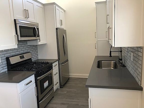 Tiled kitchen with stainless steel fridge, oven, and microwave.
