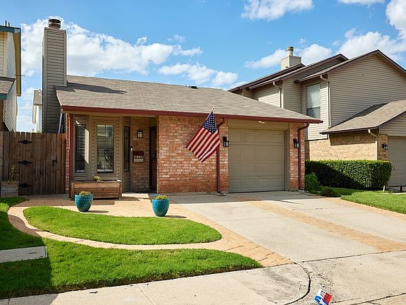 View of front facade with brick siding, concrete driveway, a garage, and roof with shingles