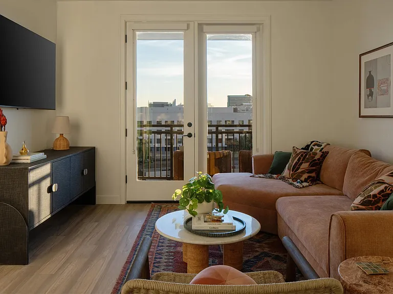 Natural light, warm finishes, and a private balcony view create a living space that feels both refined and inviting.