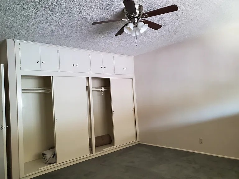 Bedroom two sliding closet doors and above storage,