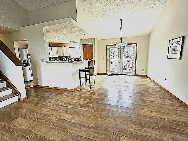 Sunlit dining area and breakfast bar counter, double doors to decking and fenced yard.