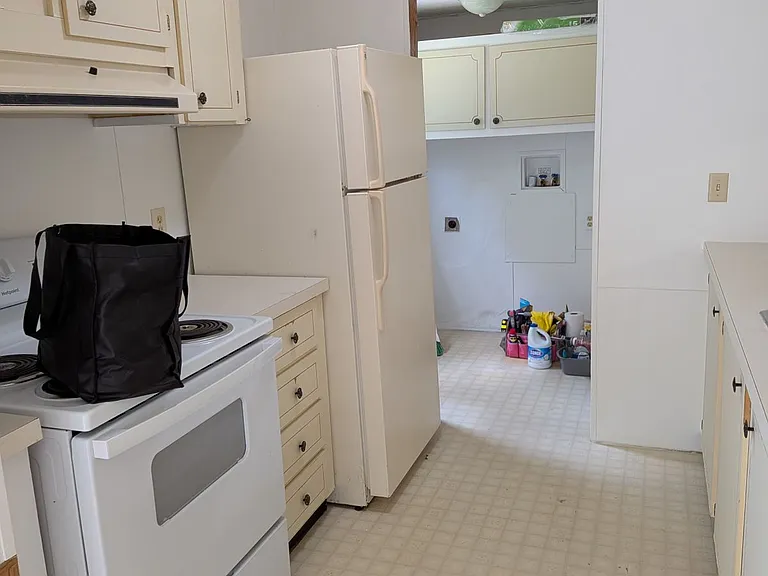 Kitchen view from dining room, leads to laundry room, pantry cabinets and back door