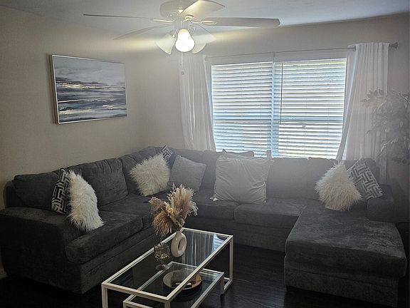 Living area featuring dark wood-style flooring and a ceiling fan