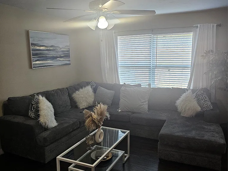 Living area featuring dark wood-style flooring and a ceiling fan