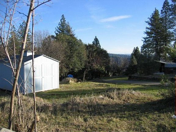 One view looking down across from the mobile home. There are several outbuildi