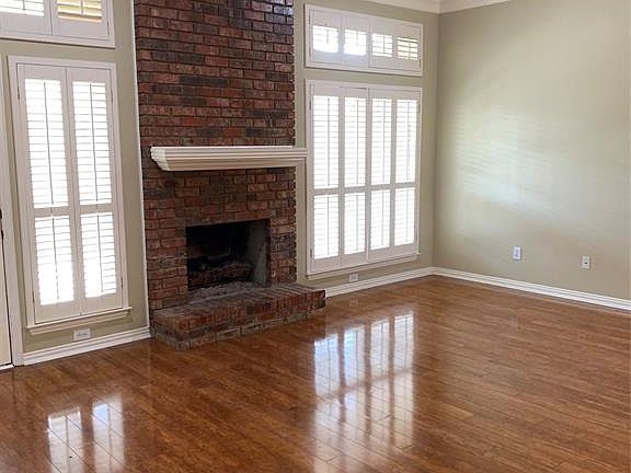 Unfurnished living room featuring a ceiling fan, hardwood / wood-style floors, ornamental molding, plenty of natural light, and a fireplace