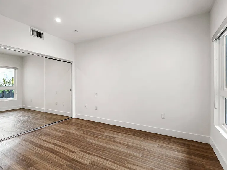 Bedroom with Mirrored Closet, Large Windows, and Vinyl Flooring