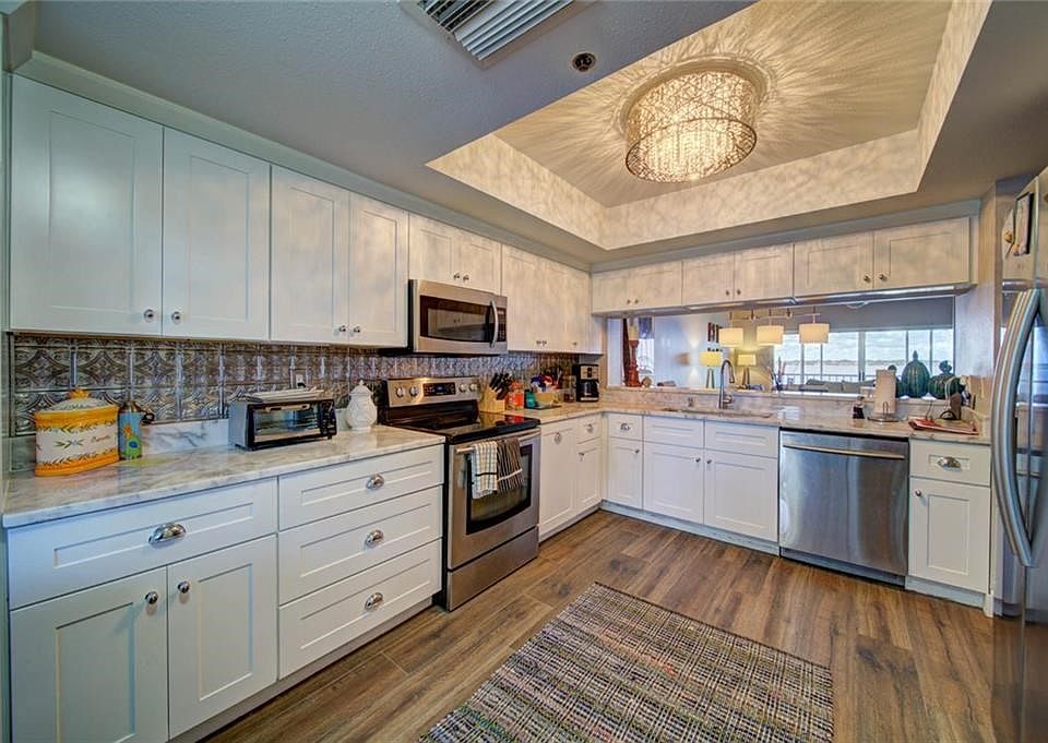 BEAUTIFULLY APPOINTED KITCHEN WITH CARARRA MARBLE CUSTOM LIGHT FIXTURE AND BACKSPLASH. STAINLESS STEEL APPLIANCES WITH AMPLE COU