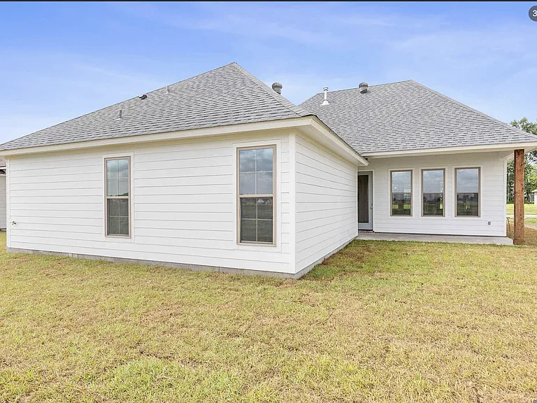 Rear view of the home showcasing covered patio, and spacious outdoor living area.