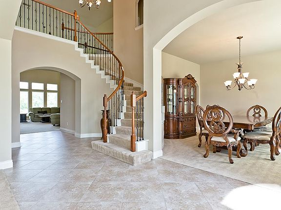 A view of the staircase and formal dining room highlighting the arched entry to the dining room and 