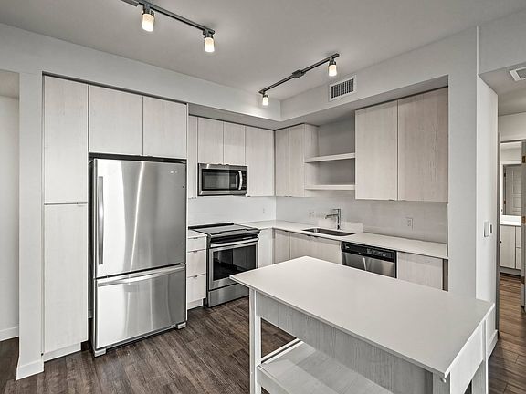Fresh light wood-toned cabinets with built-in shelving above the kitchen sink and moveable kitchen islandVacant-Unit-2