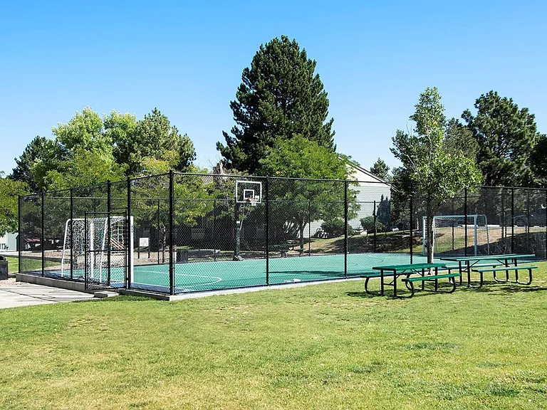 Gated sports court next to benches and grass area