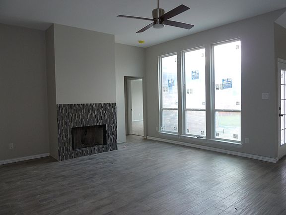 Living room, comtemporarty LED ceiling fan with remote, fireplace mantel to be installed. Tall windows look out to the patio and backyard