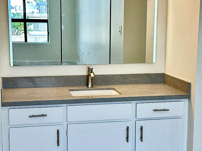 Unit #302 primary bathroom vanity with new quartzite countertops and led lit medicine cabinet with fantastic storage!