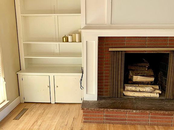 Bright living room with built in storage bookcase and wood burning fireplace