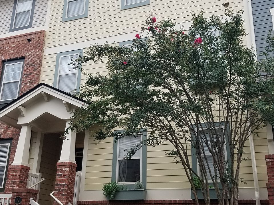 Attractive multi-story townhome with brick and siding facade, covered front porch, and blooming landscaping. Set in a quiet, walkable community near the Beltline.