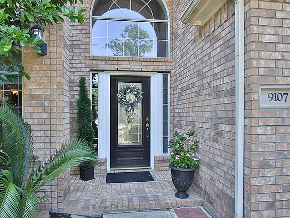 Pretty brick entrance with covered porch. Transom arched window and double sidelights.
