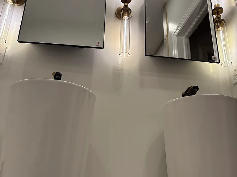 Double-sinks with a trio of brass-knurled light fixtures.