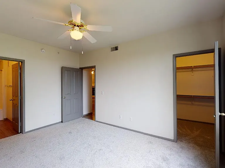 Spacious apartment bedroom with large closet and plush carpet flooring.