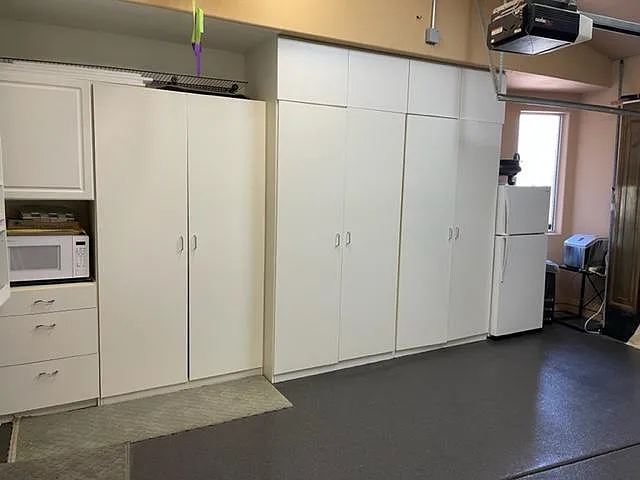 Garage wall with 2nd refrig, 2nd microwave, shelves & storage.
