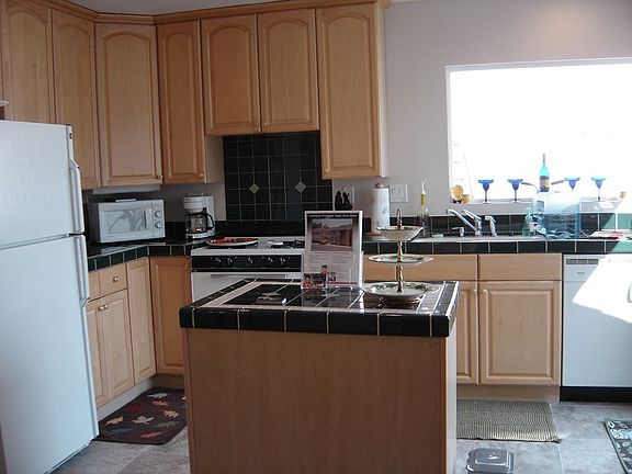 The kitchen has updated maple cabinets and tile counters.