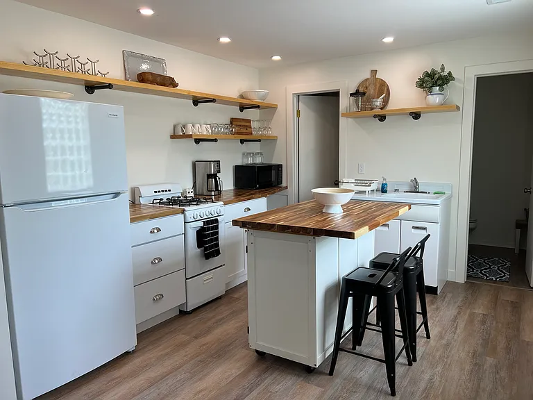 Fully equipped kitchen with refrigerator, stove, microwave, coffee maker, center island that offers seating for two and extra workspace. Kitchen is stocked with plenty of dishes, bakeware and other essential items.