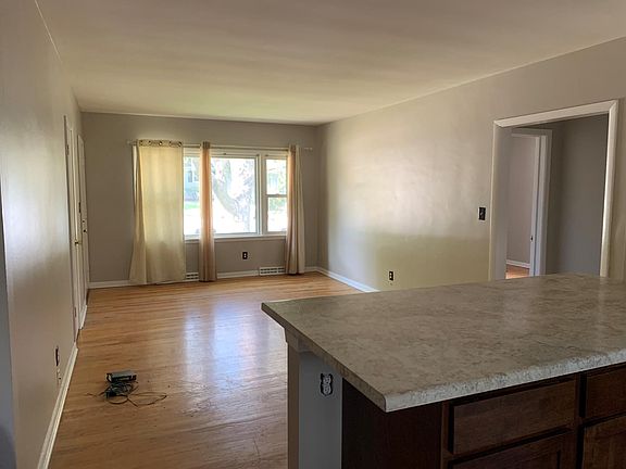 Looking into the living room from the kitchen. New cabinets and counters. Hardwood floor in living room. New LVT in kitchen.