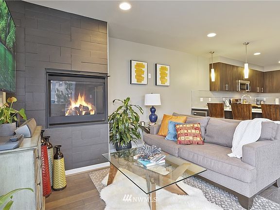 Open concept living here! The kitchen, dinning, and living rooms flow easily together. Notice the ceramic-wrapped gas fireplace and those same gorgeous wood floors.