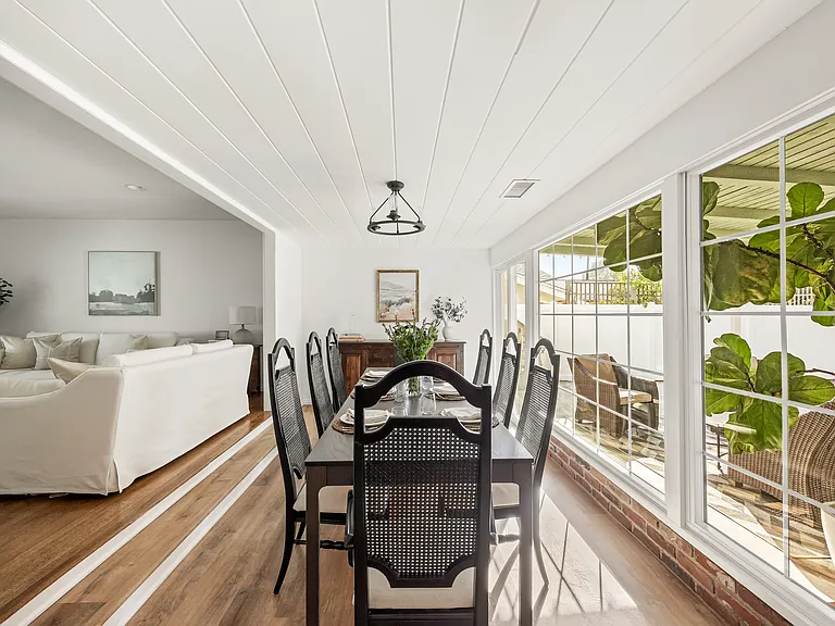 Bright dining area seating eight, seamlessly connecting both living rooms with expansive windows overlooking the backyard.