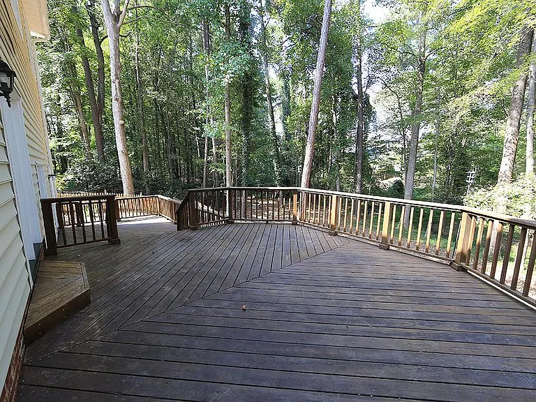 Large 2-tier deck overlooking private wooded backyard with fenced in area.