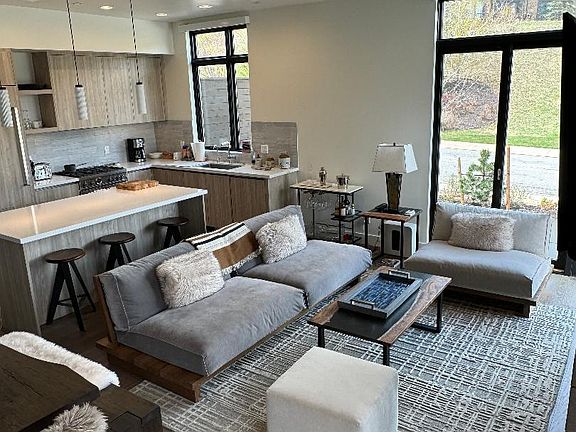 Living room and kitchen view from stairwell. 12 foot ceilings make for a very spacious and airy feeling. The kitchen island is 7 feet wide with 3 barstools.