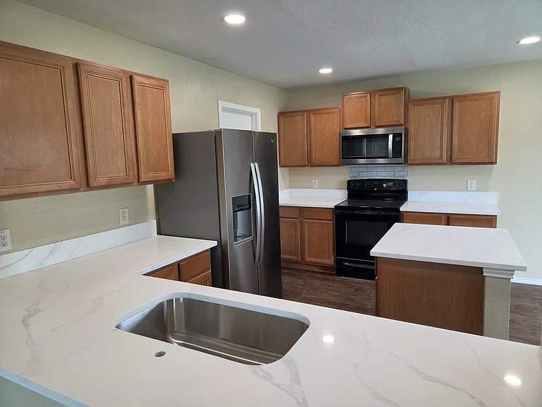 Newly remodeled kitchen with quartz countertops, recessed lighting and stainless appliances