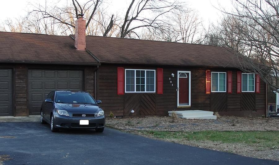 Brown wood siding with red door and shutters