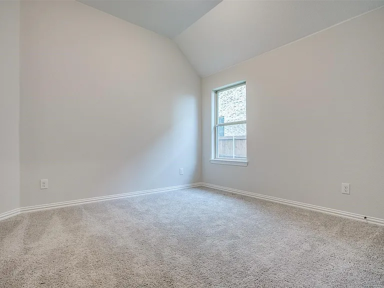 Carpeted interior space featuring a single window and vaulted ceiling