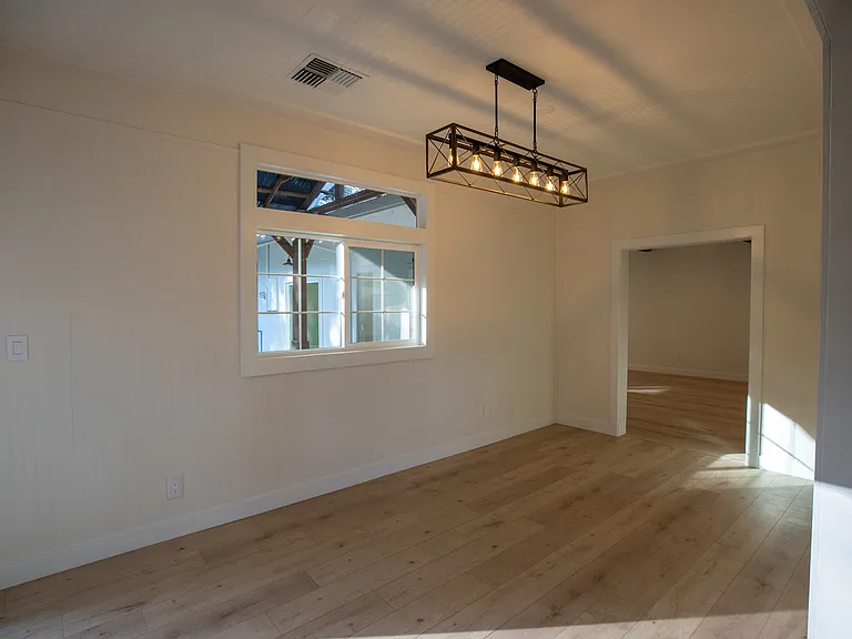 Formal dining room with door to exterior covered patio and new fixture. Imagine a family meal or dinner part in these bright high ceilings.