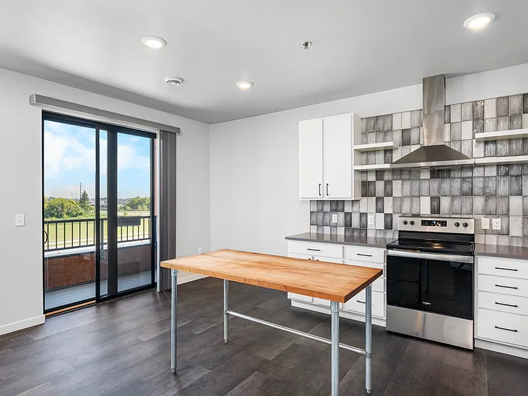 Modern kitchen with sleek stainless steel appliances, elegant white cabinetry, and a spacious wooden island, complemented by a scenic balcony view. Modern kitchen with sleek stainless steel appliances, elegant white cabinetry, and a spacious wooden island
