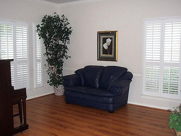 The formal living room features plantation shutters and a wood grain laminate floor.