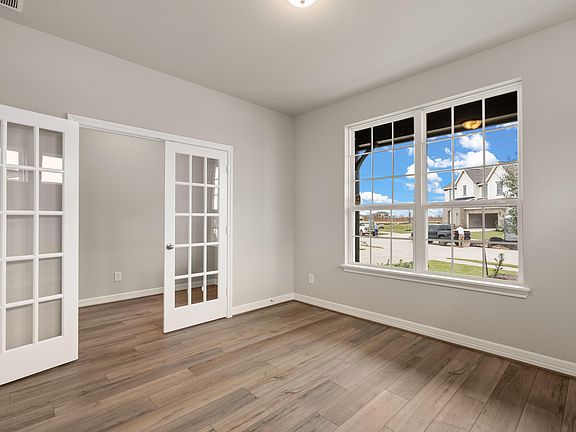 An additional view of the home office featuring French doors, beautiful flooring and neutral paint.