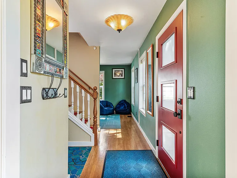 The front entry opens to the stairwell and hallway ahead, the main floor office to the right, and the living room to the left.