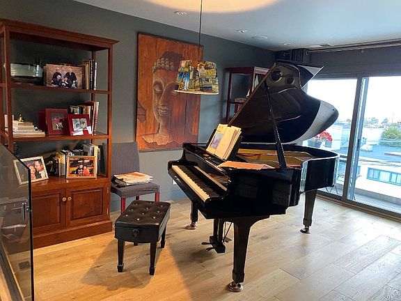 Grand piano in living room with a city skyline view and balcony'