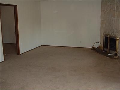 Living room has corner wood fireplace and ceiling fan.