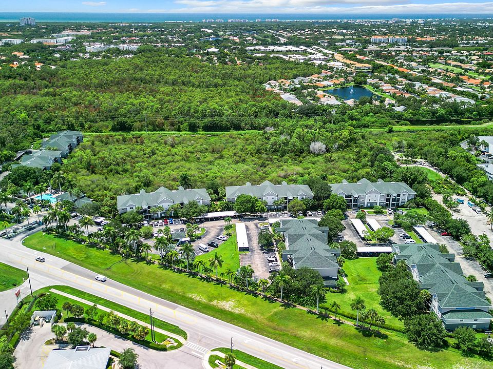 An expansive aerial view of our beautiful community, illustrating the balance of lush green surroundings and proximity to local amenities such as Barefoot Beach, making it an ideal place to call home.