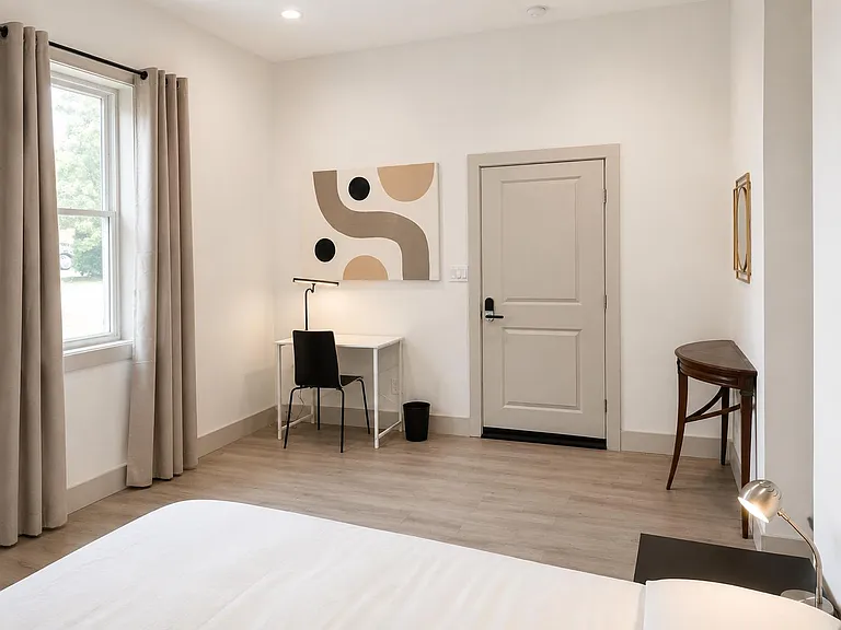Bedroom with a large window, neutral finishes, and space for a desk setupideal for working or studying at home.
